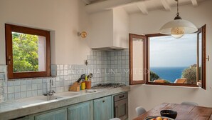 Una cocina con vista al mar, una mesa de comedor con fruta y una ventana con vista.