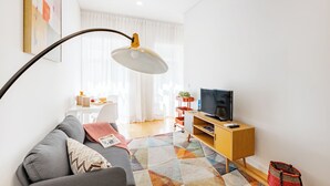 Un salon moderne avec un canapé, un téléviseur, une lampe et un tapis coloré.