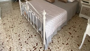 Une chambre à coucher comprenant un lit, une table de chevet, une commode, un lustre, un canapé et un tableau accroché au mur.
