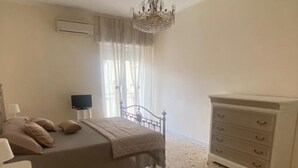 Une chambre à coucher comprenant un lit, une commode, un téléviseur et un lustre.