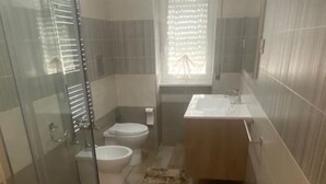 Une salle de bain compacte avec une douche à parois de verre, des toilettes et un lavabo.