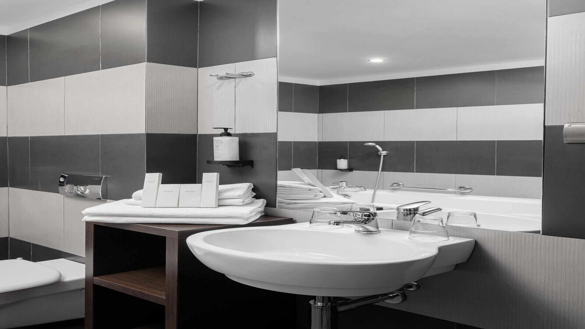 Un baño moderno con lavamanos blanco, espejo y zona de ducha.
