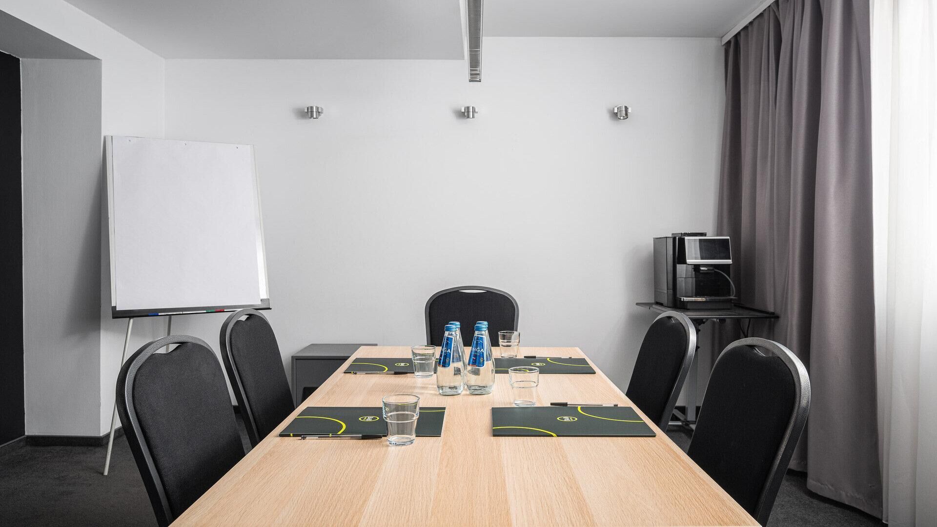 Una sala de conferencias con una larga mesa, sillas, una pizarra y una máquina de café.