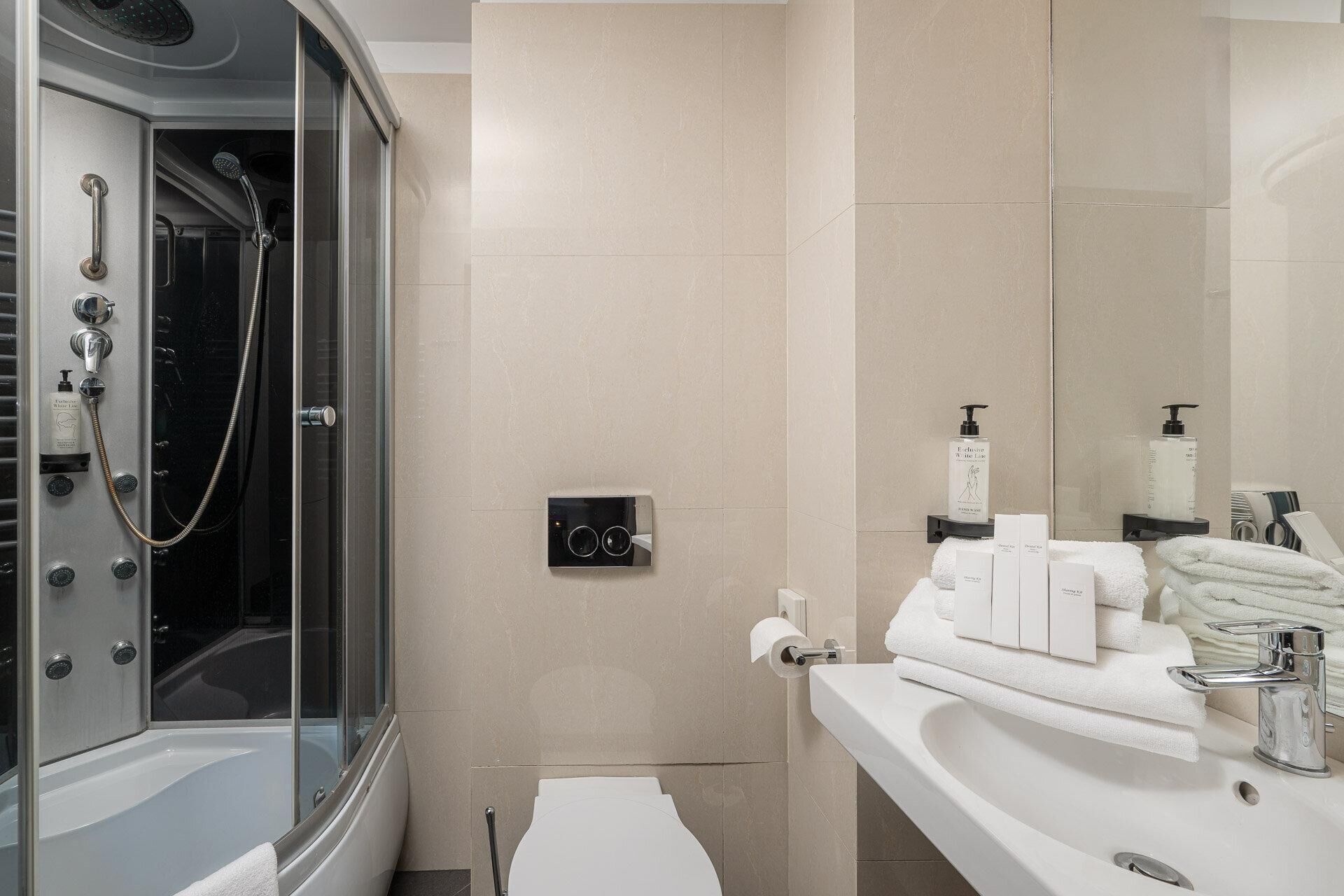 Une salle de bain moderne avec une douche à parois de verre, un meuble-lavabo avec des articles de toilette et des toilettes.