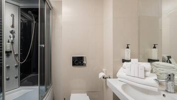 Une salle de bain moderne avec une douche à parois de verre, un meuble-lavabo avec des articles de toilette et des toilettes.