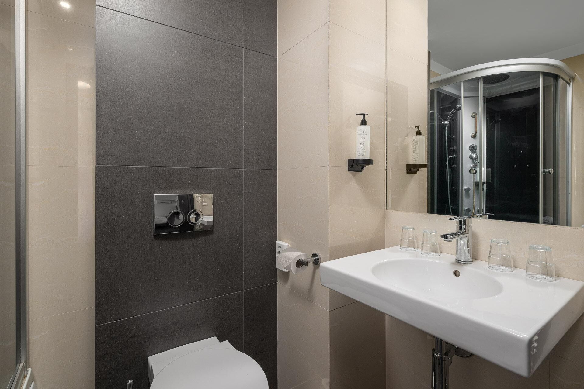 A modern bathroom with a white sink, a glass shower enclosure, and a toilet.