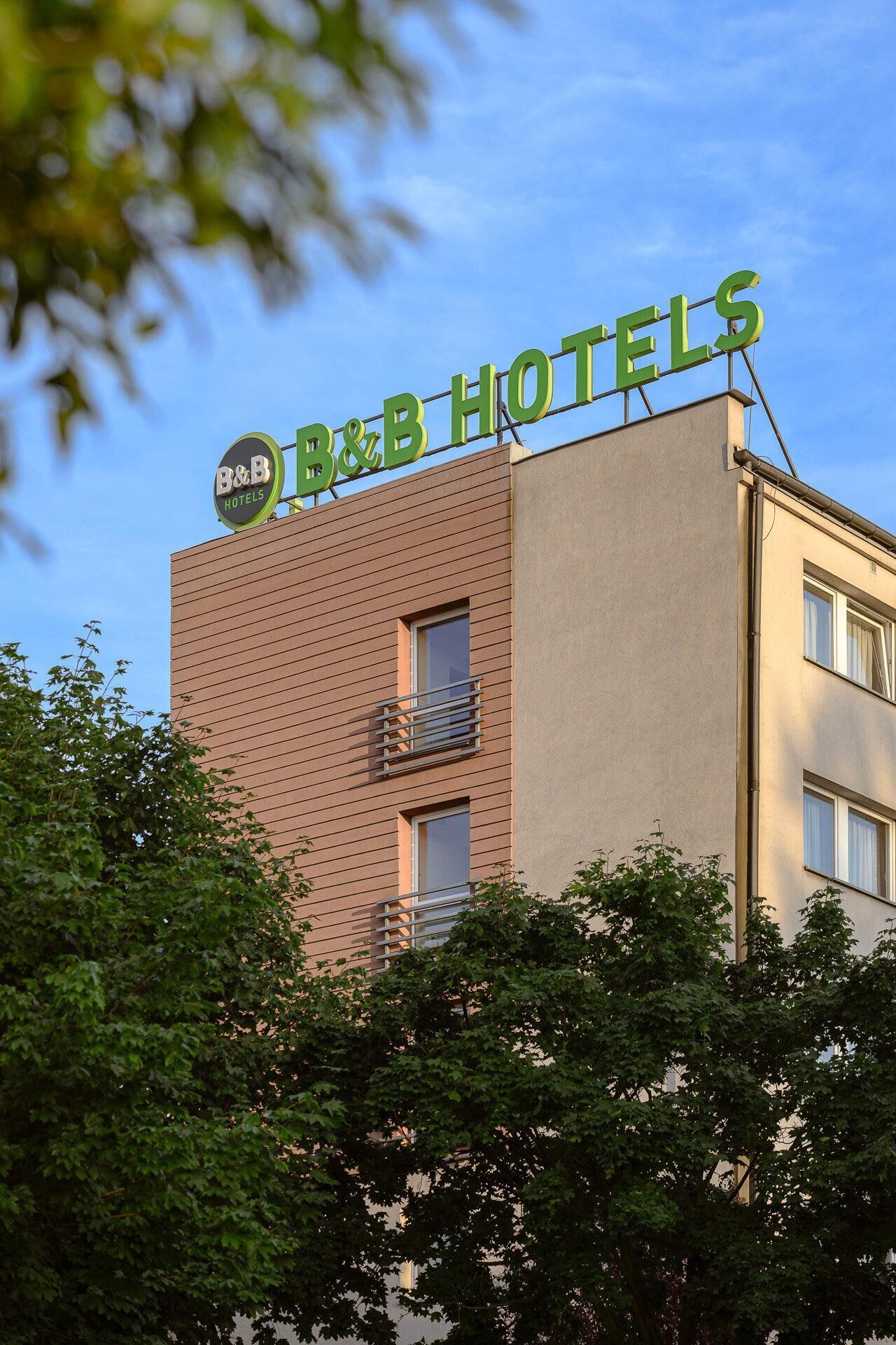 Un hôtel de type « bed and breakfast » avec une enseigne bien visible, une façade en briques et un balcon.