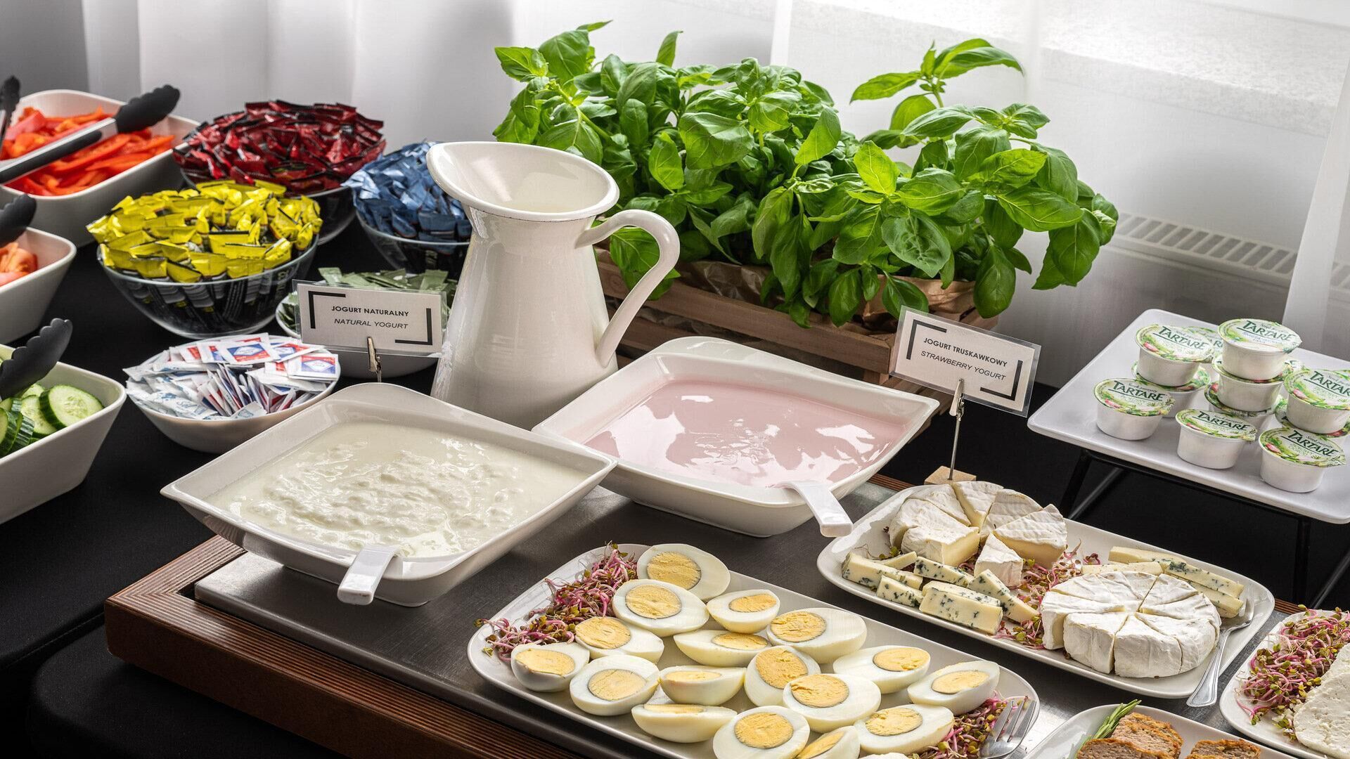 A buffet with various food items including yogurt, cheese, and eggs.