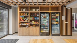 A BB shop with wooden shelving stocked with snacks and beverages, and two refrigerated display cases. - B&B HOTEL Bytom (Bytom)