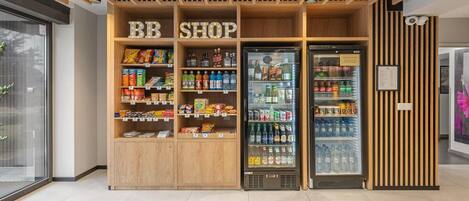 A BB shop with wooden shelving stocked with snacks and beverages, and two refrigerated display cases.