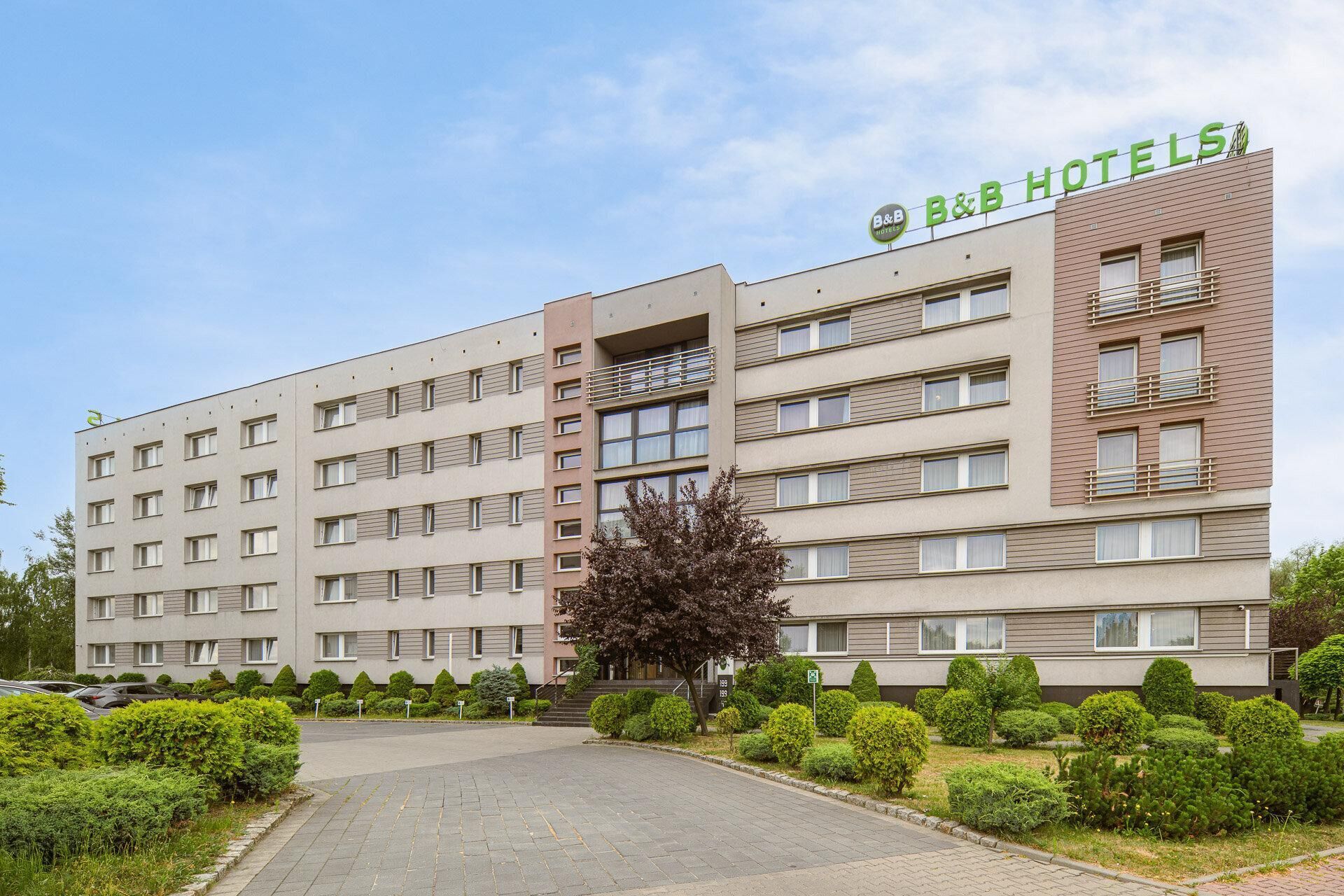 A multi-story B&B hotel with a flat facade, balconies, and a well-maintained garden.