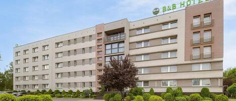 A multi-story B&B hotel with a flat facade, balconies, and a well-maintained garden.