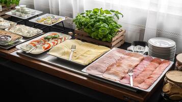 A buffet with various cheeses, cured meats, and a basil plant.