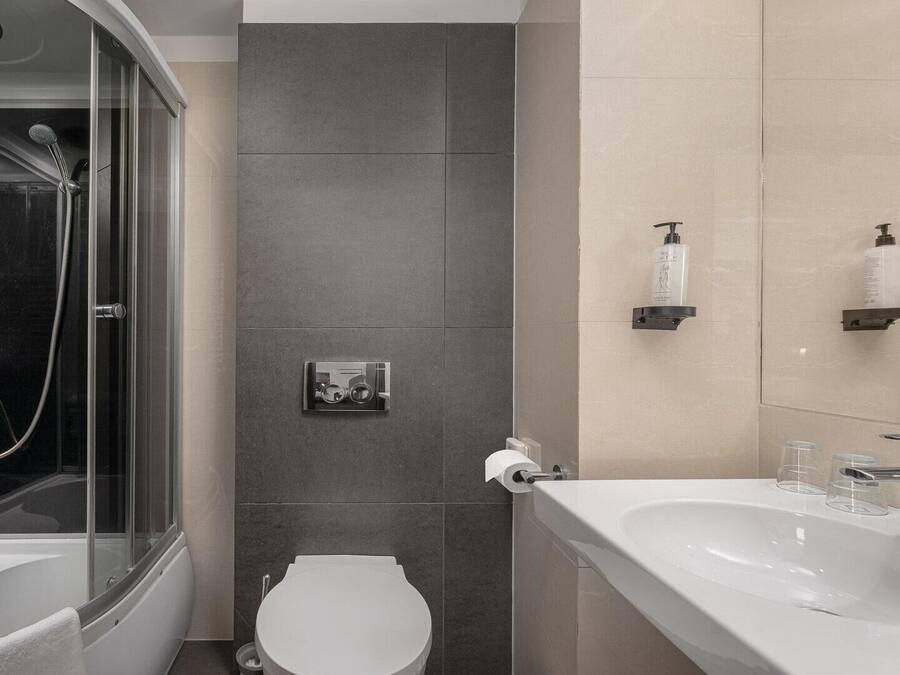 A modern bathroom with a glass-enclosed shower, a toilet, and a sink with a mirror.
