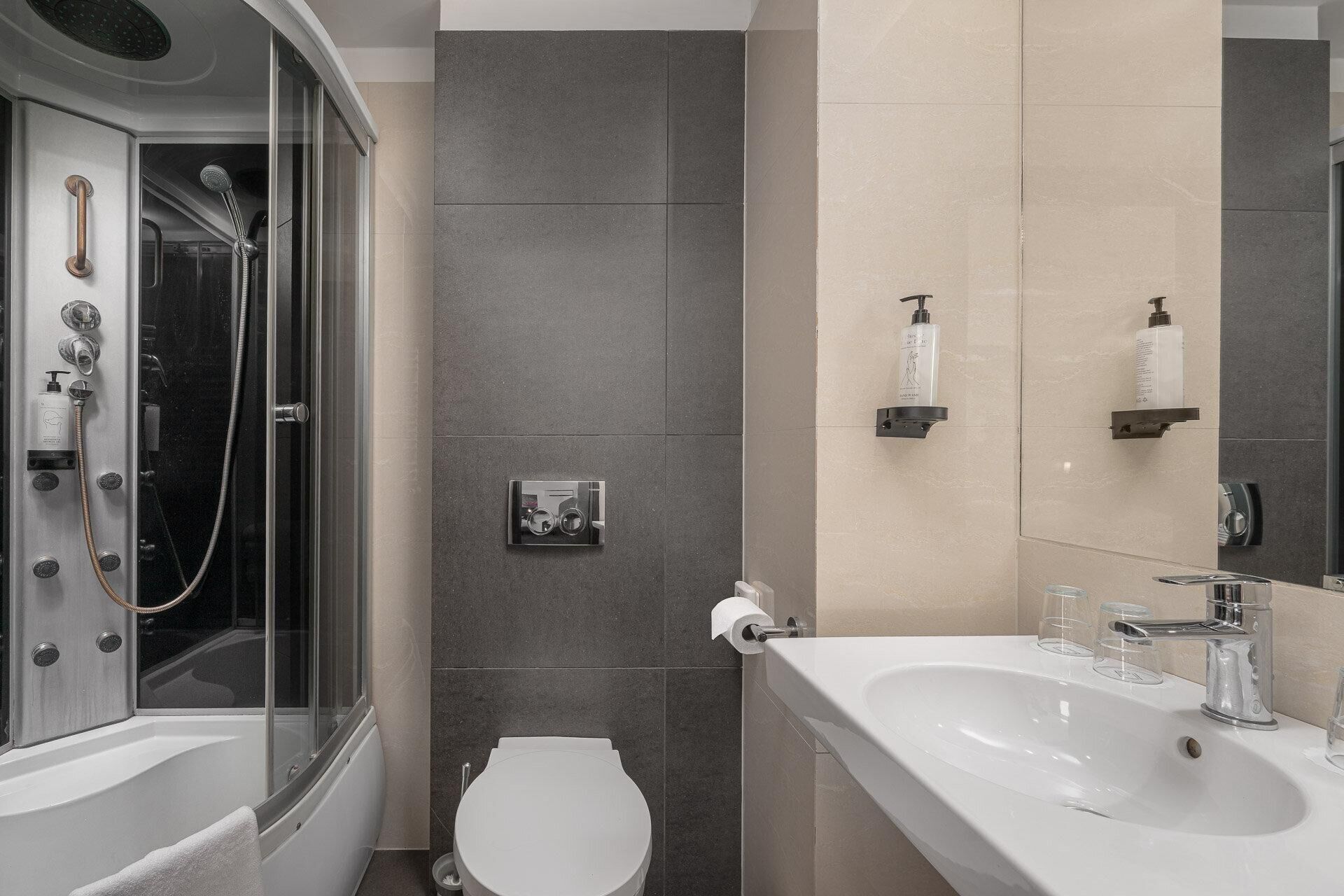 A modern bathroom with a glass-enclosed shower, a white toilet, and a vanity with a sink and mirror.
