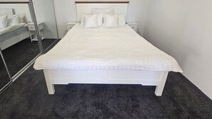 A neatly arranged bedroom with a bed, bedside tables, and a large mirror. - Guest Suite Bredbo (Jerangle)