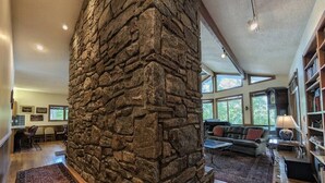 Ein großzügiger Wohnbereich mit Kamin aus Stein, Holzboden und einem großen Fenster für natürliches Licht.
