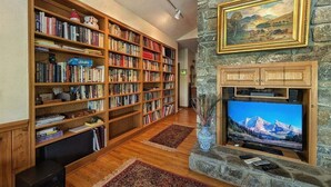 Ein Wohnzimmer mit Kamin, Bücherregalen, Fernseher und einer Steinwand.