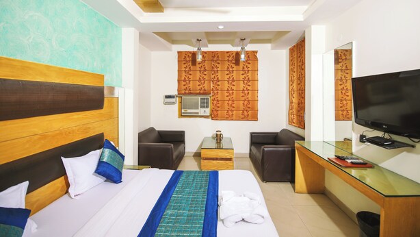 A hotel room with a bed, two sofas, a TV, a coffee table, and a desk. - Hotel Lav Kush Deluxe (New Delhi)