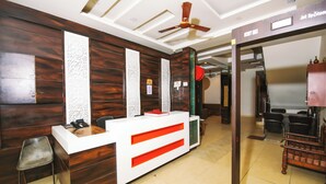A reception desk with a modern design, a ceiling fan, and a security desk. - Hotel Lav Kush Deluxe (New Delhi)