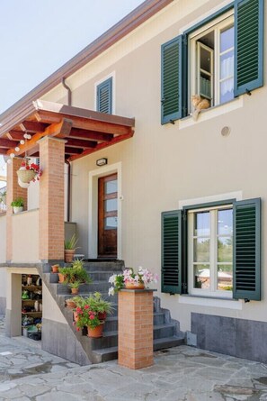 Ein Haus mit Veranda, Treppen und Blumentöpfen.