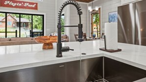 Eine Küche mit einem modernen Wasserhahn, einer Holtschüssel auf der Arbeitsfläche und einem Schild mit der Aufschrift 'Playin' Fond'.