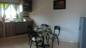 A compact kitchen with a dining table and chairs, a refrigerator, and a microwave. - Yopal Apartment (Medellín)