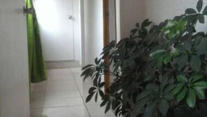 A hallway with a tiled floor, a potted plant, a green curtain, and a door with a sign. - Yopal Apartment (Medellín)