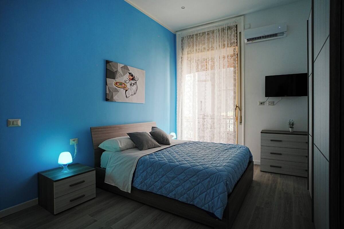 Ein Schlafzimmer mit einem Bett, Nachttischen, einem Fernseher und einem Bild an der Wand.