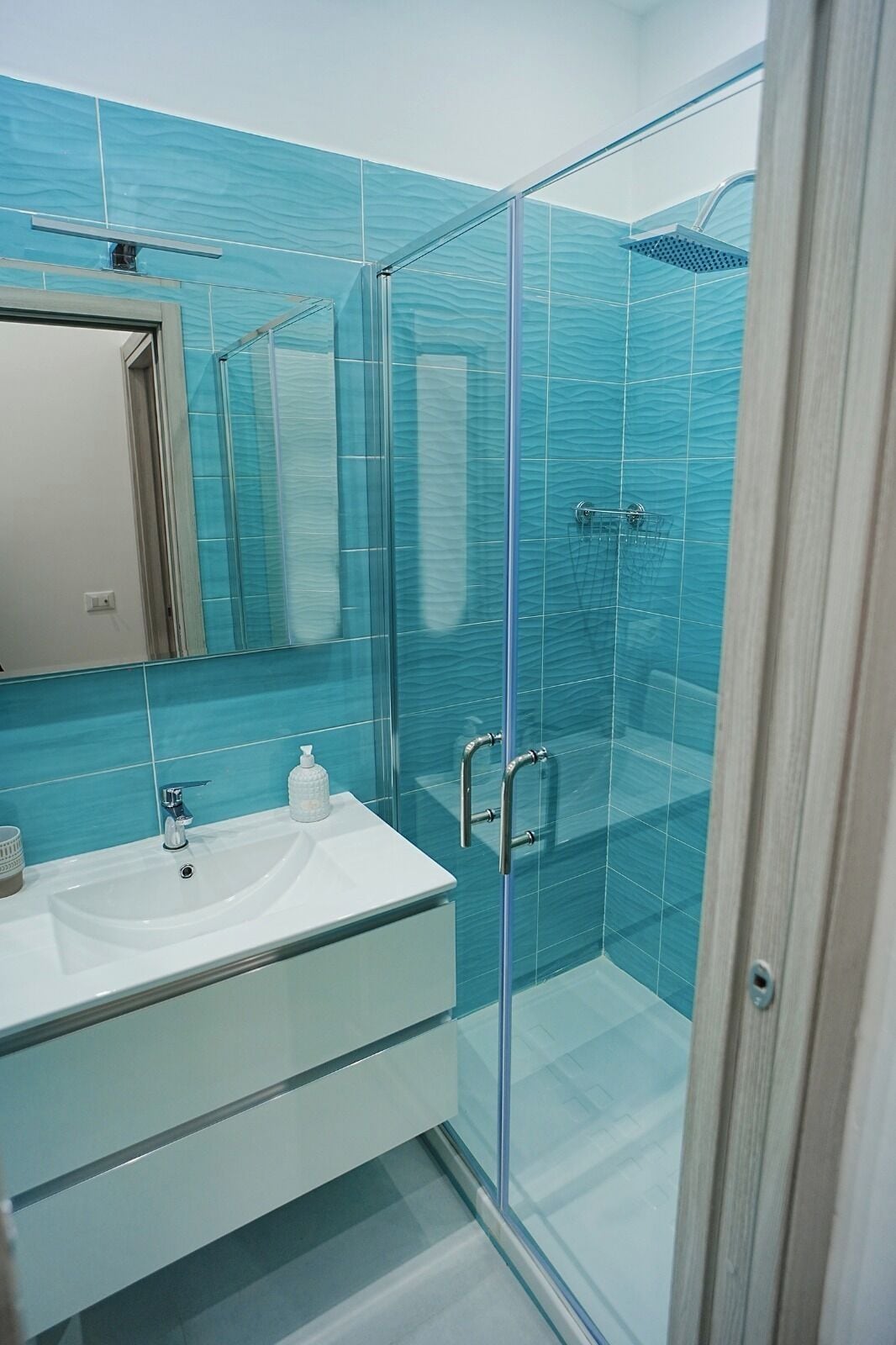 Ein modernes Badezimmer mit Duschkabine aus Glas, einem weißen Waschbecken und einem Spiegel.