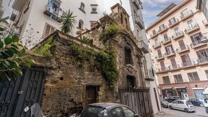 Una calle estrecha con edificios antiguos, un coche aparcado y una motocicleta.