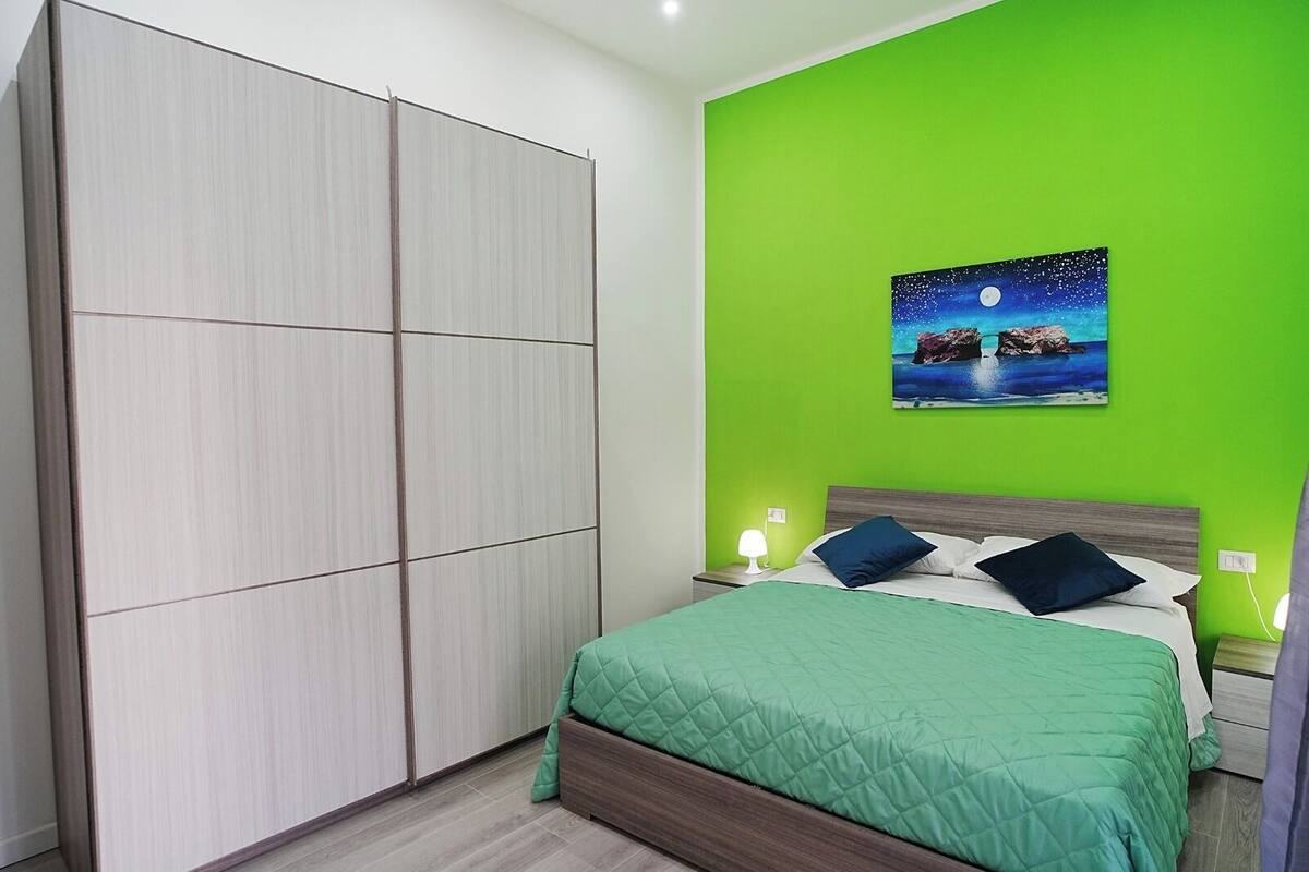 Ein Schlafzimmer mit Bett, grünen Wänden, einem Gemälde mit Nachthimmel und einem Kleiderschrank.