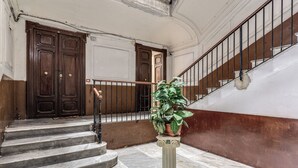 Una escalera de mármol con una planta en maceta, puertas de madera y una barandilla de metal.
