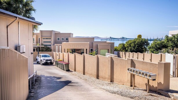A residential area with a parking lot, a row of mailboxes, and a bridge in the background. - Modern, fully equipped, and pet-friendly accommodation. (Port Lincoln)