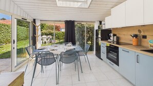 Une cuisine moderne avec une lucarne, un coin repas avec des chaises et une vue sur le jardin.