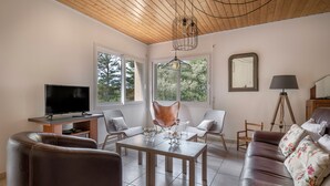Un salon équipé d’un téléviseur, d’un canapé en cuir, d’une table basse en bois et de deux fauteuils.