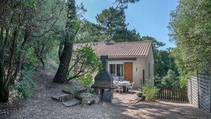 Une maison de campagne au toit en tuiles, dotée d’une cheminée et d’un patio aménagé avec une table et des chaises.