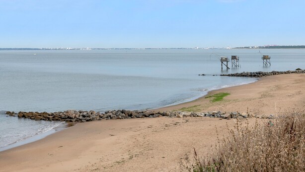 Une plage dotée d’une digue rocheuse et de deux structures en bois.