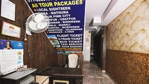 A travel agency desk with a large sign listing tour packages and services like flight, bus, and taxi bookings. - Hotel Jindal  (New Delhi)