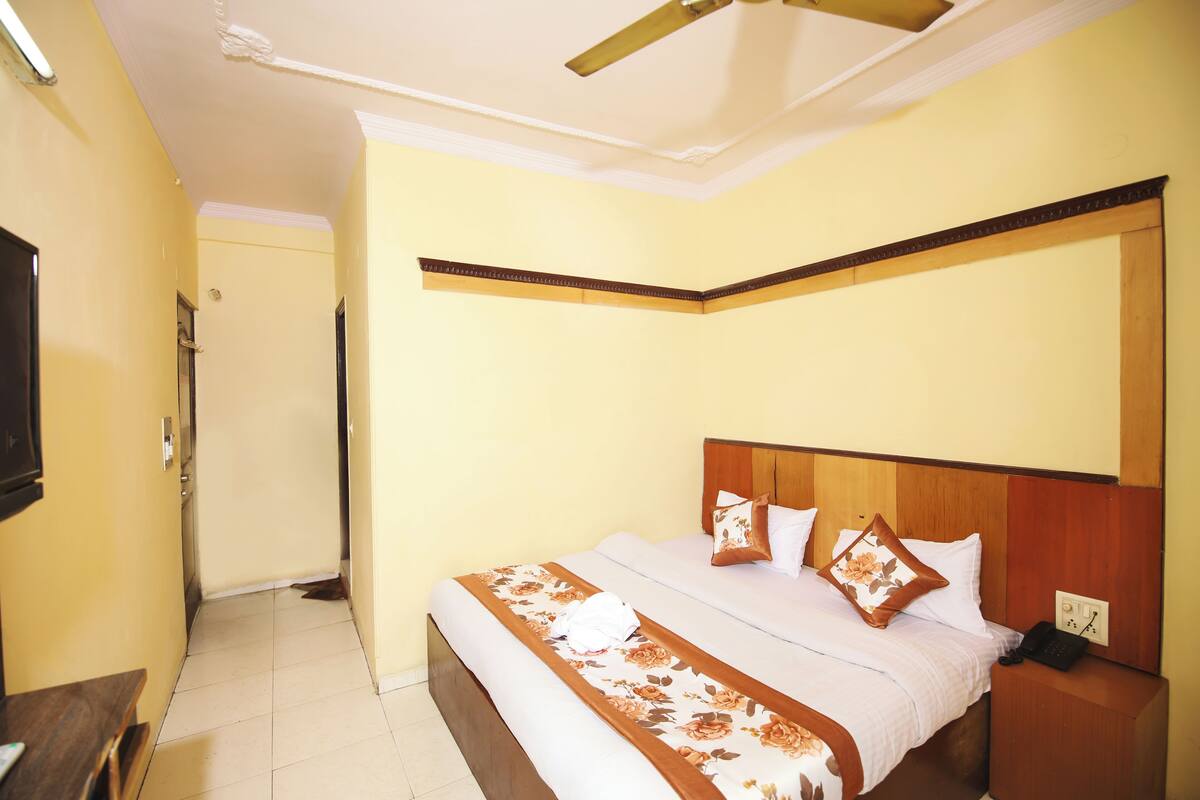 A hotel room with a bed, bedside table, and a ceiling fan.