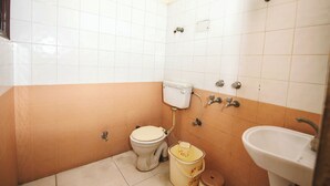 A small bathroom with a toilet, sink, and shower. - Hotel Jindal  (New Delhi)