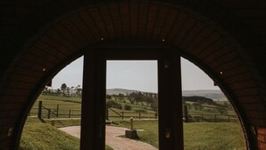 An arched doorway leading to a grassy landscape with a brick pathway. - Otters View (Rhayader)