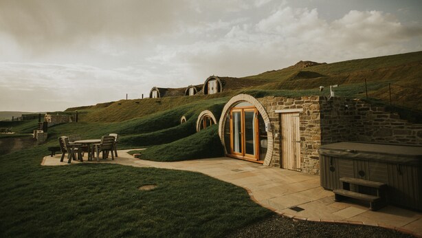 A stone building with arched doorways and a patio area with a table and chairs. - Otters View (Rhayader)