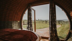 A bedroom with a large window, a bed, and a view of a grassy field. - Otters View (Rhayader)