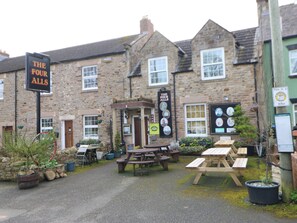 A stone building with a sign reading "The Four Alls" and outdoor seating. - Appletree Cottage (Richmond)