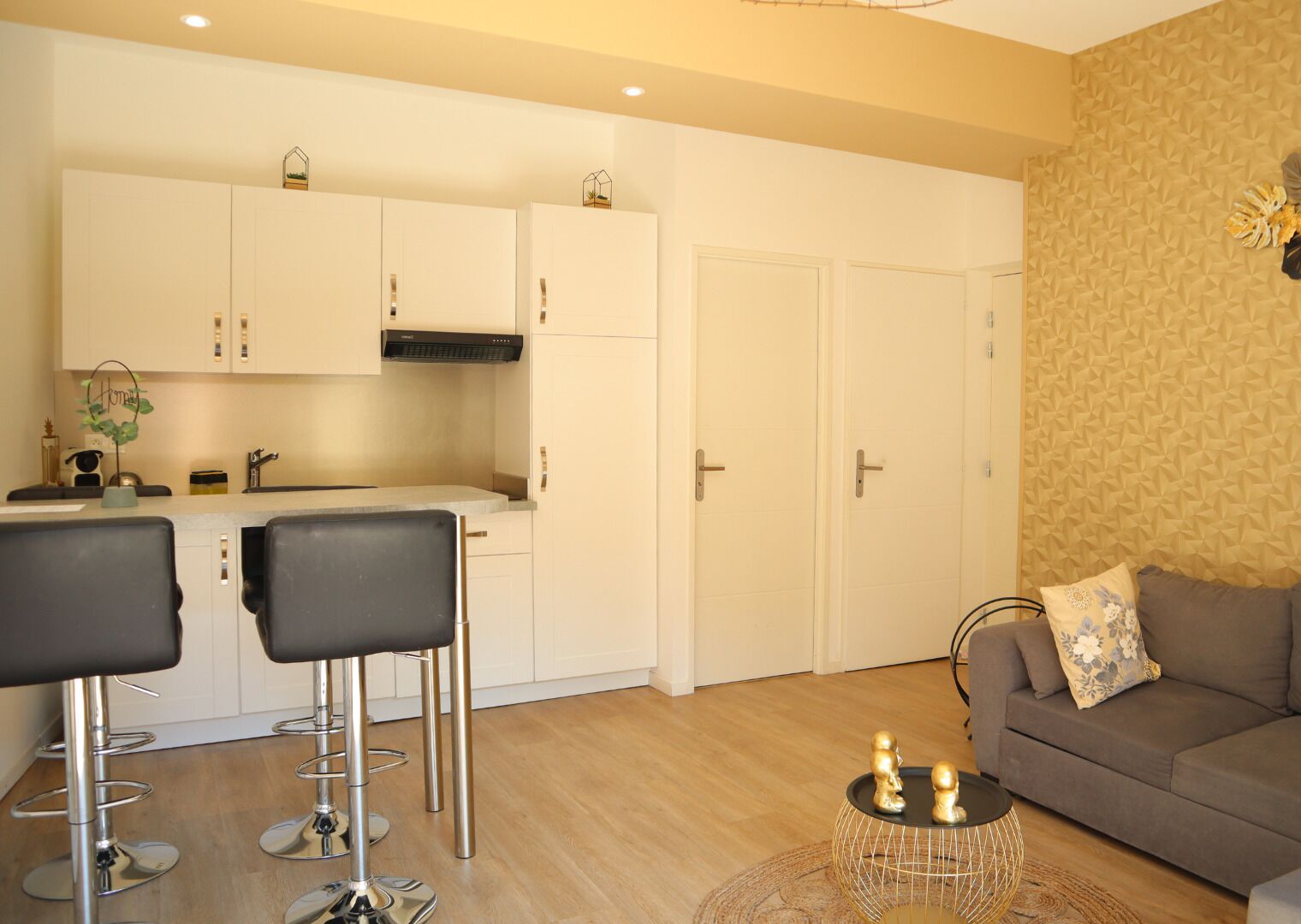 A modern kitchen with white cabinets, a built-in stove, and a dining area with two bar stools.