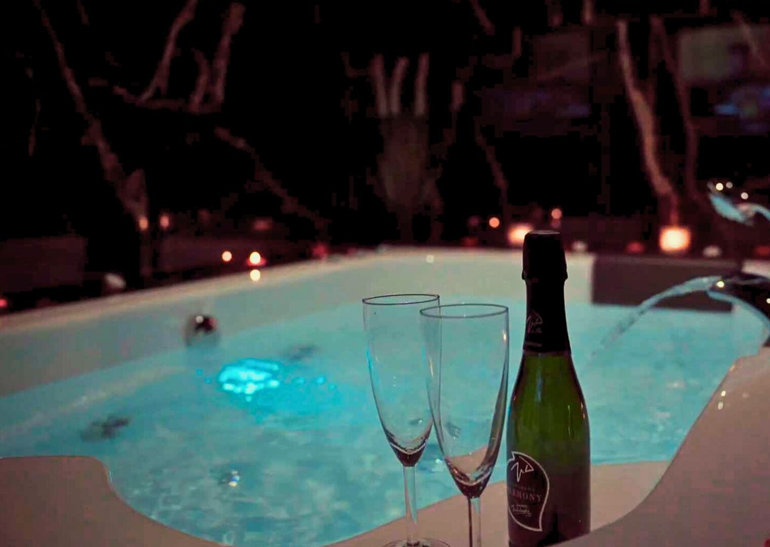 A hot tub with two glasses and a bottle of champagne.