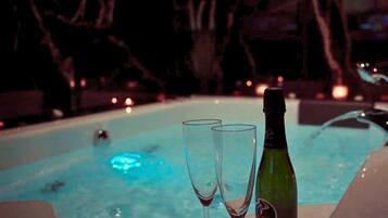 A hot tub with two glasses and a bottle of champagne.