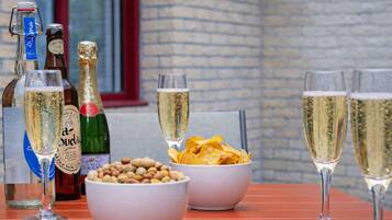 A table with bottles of beverages, glasses of champagne, and bowls of snacks.