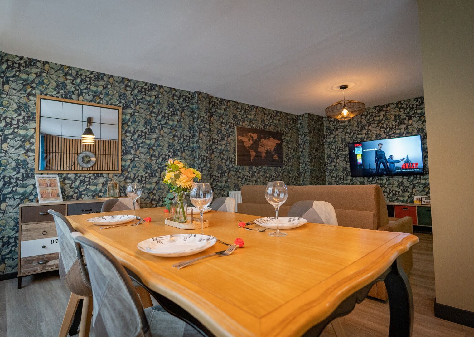 Un comedor con una mesa de madera, sillas y un televisor montado en la pared.